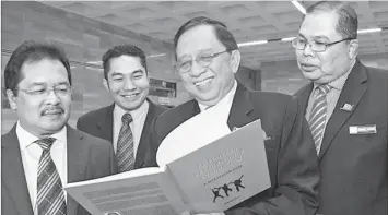  ??  ?? Karim (second right) reads a management book given to him by MPC. Also seen from left are Basimin, Norjayadi and Fadzil. - Photo by Chimon Upon