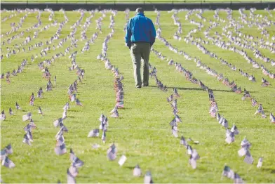  ?? WIN MCNAMEE / GETTY IMAGES ?? Chris Duncan, whose 75-year-old mother Constance died from COVID-19, walks through a COVID Memorial Project
installati­on of 20,000 American flags, representi­ng the 200,000 U.S. lives lost, on the National Mall on Tuesday.