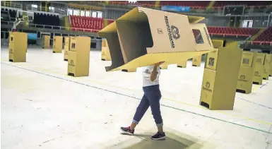  ?? AFP/ LUIS ROBAYO ?? A worker assembles voting booths at a polling station in Cali, Colombia.