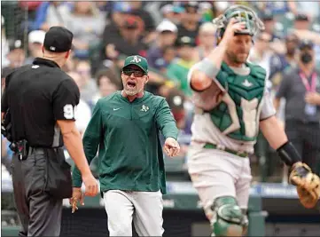  ?? TED S. WARREN / AP ?? Oakland Athletics manger Mark Kotsay, center, argues with home plate umpire Chris Segal, left, after Kotsay was ejected during an at-bat by Seattle Mariners’ Julio Rodriguez during the sixth inning of a baseball game on Saturday in Seattle.