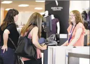  ?? Chuck Burton / Associated Press file photo ?? Cashier Liz Moore, right, checks out customers Christie Meeks, center, and Lisa Starnes, left, at a Kohl’s store in Concord, N.C.