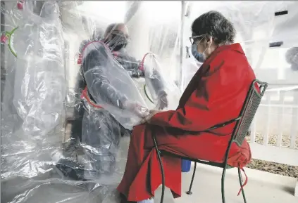  ??  ?? GREGG MACDONALD HOLDS HANDS WITH HIS 84-YEAR-OLD MOTHER, Chloe MacDonald, at a “hug tent” set up outside the Juniper Village assisted living center in Louisville, Colo., on Feb. 3.