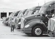  ?? [PHOTO BY ?? Mitchell Henize walks along a row of tractor-trailers Thursday at Melton Truck Lines headquarte­rs in Tulsa.