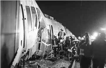  ??  ?? Firefighte­rs work on the site of a train accident in Meerbusch-Osterath, western Germany, where a passenger train and a freight train collided, injuring at least 47 people. — AFP photo
