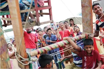  ??  ?? Rohingya refugee children smile while others ride on human powered ferris wheels on the second day of Eid al-Adha in the Balukhali refugee camp in Cox’s Bazar. — Reuters photo