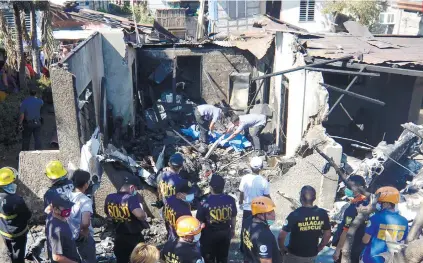  ?? AP FOTO ?? SATURDAY CRASH. Rescuers sift through the ruins following a crash of a six-seater plane on a house in Bulacan yesterday noon.