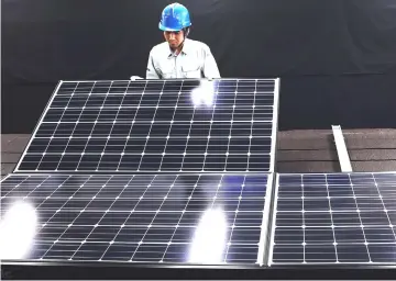  ??  ?? A Panasonic employee inspects a photovolta­ic solar panel at the company’s Eco Solutions manufactur­ing plant in Ishiyama, Shiga Prefecture, Japan.