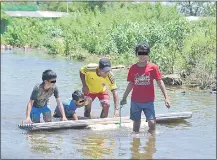  ??  ?? En el Banco San Miguel, niños ayudan a su padre a llevar, flotando, chapas que serán parte de su refugio.