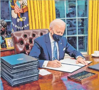  ?? DOUG MILLS
/ EFE ?? Washington. El presidente Joe Biden firma órdenes ejecutivas en el Despacho Oval de la Casa Blanca.