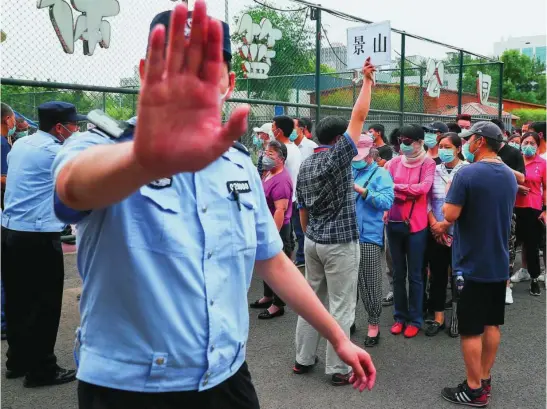  ?? REUTERS ?? Un policía gesticula mientras un grupo de personas hace fila para hacerse una prueba en un centro deportivo tras un pico de casos por coronaviru­s en Pekín