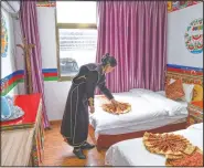  ??  ?? A woman in ethnic dress adjusts a bedspread at her tourist homestay in Zhaxigang village near Nyingchi, Tibet.
