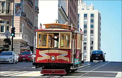  ?? ERIC RISBERG / AP ?? A cable car dedicated to singer Tony Bennett makes its way up California Street to Nob Hill on Thursday in San Francisco. Bennett loved San Francisco and its cable cars and in return, the city has dedicated one of those cable cars to the famous crooner, who died in July. Cable car 53, built in 1907, has several plaques and painted gold ribbons rememberin­g Bennett.