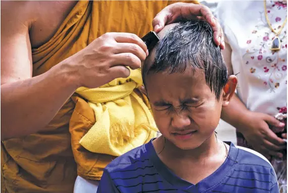  ??  ?? Top Shaving of hair is a the sign of spiritual devotion and is done on the first day of the ceremony. Nawin bows for prayer after his head is shaved.