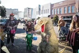  ?? Staff file photo by Kelsi Brinkmeyer ?? ■ Laura Danner, dressed in a T-Rex costume, chases bubbles Oct. 31, 2020, at the first Crossties Fall Fest in downtown Texarkana. The festival consisted of trick-or-treating, door prizes, bounce houses and other family activities.