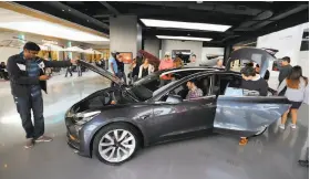  ?? Allen J. Schaben / Los Angeles Times ?? The Tesla showroom in Century City, near Los Angeles, features the Model 3. Founder Elon Musk (left) now says he’ll be sticking with the company.
