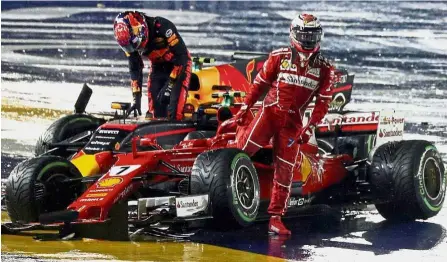  ?? — Reuters ?? Premature exit: Red Bull’s Max Verstappen (left) and Ferrari’s Kimi Raikkonen getting out of their cars after crashing out of the race at the Singapore Grand Prix on Sunday. Below: Ferrari’s Sebastian Vettel reacting after retiring from the race.