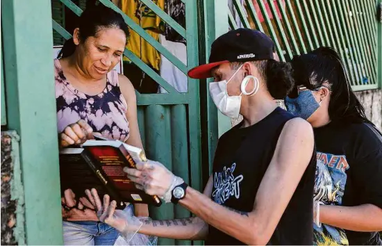  ?? Guilherme Martimon/Grace ?? Voluntário­s entregam livros com cestas básicas em Recanto das Emas, no Distrito Federal