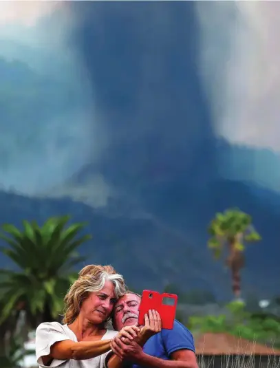  ?? REUTERS ?? Una pareja se hace un selfie delante del volcán en la localidad de Los Llanos