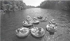  ??  ?? A flotilla of friends from Biddeford, Maine, raft down the Saco River at Bar Mills in Buxton, Maine, on Sunday. Temperatur­es are expected to hover around the 90s for the next few days.