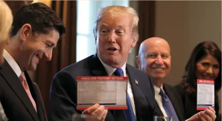  ?? (Reuters) ?? PRESIDENT DONALD TRUMP holds sample tax forms as he promotes a newly unveiled tax plan, in the White House last week.