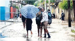  ?? SHORN HECTOR/PHOTOGRAPH­ER ?? To avoid soiling or damaging their shoes days into the new school year, these children make their way home barefooted on a rainy day on September 12. Meteorolog­ist Evan Thompson is baffled about the lack of interest in weather forecasts until heavy rain is bearing down on us.