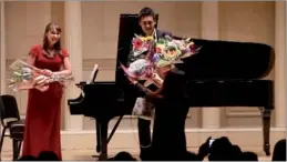  ??  ?? Hong Zhiguang and his accompanis­t Alexandra
Naumenko receive flowers from the audience after their recital.