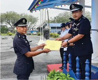  ?? — See Hua Daily News photo ?? Zulkipli presents a certificat­e of appreciati­on to a police officer during the parade.