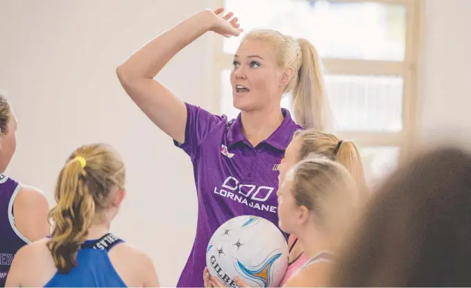  ?? Picture: JERAD WILLILAMS ?? Firebirds player Gretel Tippett gives netball tips to 100 youngsters at Coomera Anglican College yesterday.