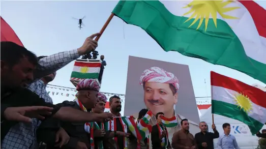  ?? AFP ?? Iraqi Kurds next to a poster of the president of Iraq’s Kurdistan region urge people to vote in the independen­ce referendum in Erbil in September
