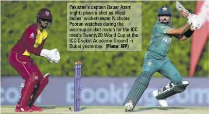  ?? (Photo: AFP) ?? Pakistan’s captain Babar Azam (right) plays a shot as West Indies’ wicketkeep­er Nicholas Pooran watches during the warmup cricket match for the ICC men’s Twenty20 World Cup at the ICC Cricket Academy Ground in Dubai yesterday.