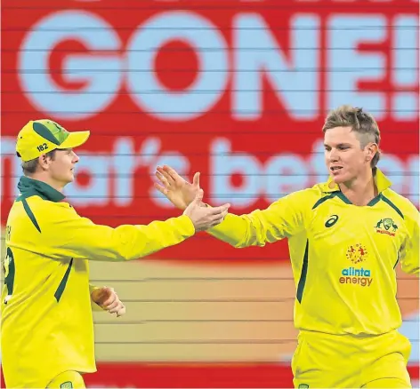  ?? ?? GOOD JOB: Australia’s Adam Zampa, right, celebrates with teammate Steve Smith after taking the wicket of England’s Jos Buttler during the match at the MCG.