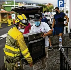  ?? EMILIO MORENATTI/ASSOCIATED PRESS ?? Residents remove their belongings from their houses Wednesday as lava from a volcano eruption flows, forcing them to evacuate their village on the Spanish island of La Palma in the Canaries.