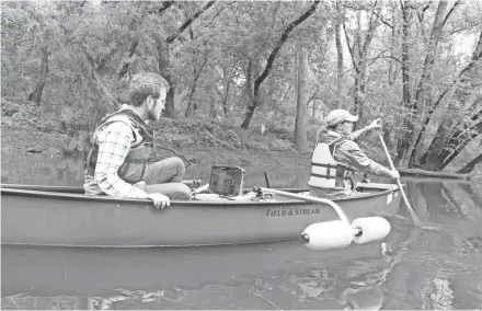  ?? PAUL A. SMITH ?? Beth Wentzel paddles a canoe on the Milwaukee River near Thiensvill­e while Ryan Miller monitors a side-scan sonar unit during a fish habitat mapping project on the river in Ozaukee County. Wentzel and Miller are employees of the Ozaukee County Planning and Parks Department. The work is focused on assessing the river for potential spawning sites for lake sturgeon, a native species that is being stocked as part of a restoratio­n effort.