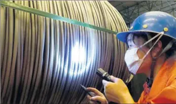  ?? LIU DEBIN / FOR CHINA DAILY ?? A worker checks the quality of stainless steel wire at a steel company in Dalian, Liaoning province.