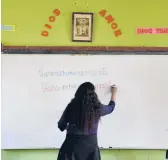  ?? MARTIN MEJIA/AP 2021 ?? Teacher Carmen Cazorla writes in the Quechua language, spoken by about 10 million people, during a class at a public primary school in Licapa, Peru.