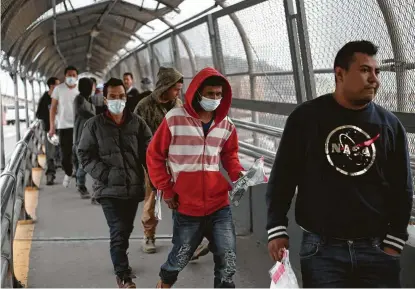  ?? Christian Chavez / Associated Press ?? Central American migrants seeking asylum at the end of March, some wearing protective face masks, return to Mexico via the internatio­nal bridge at the U.S-Mexico border that joins Ciudad Juarez and El Paso.