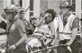  ??  ?? Rescue workers carry victims on stretchers Saturday after a car plowed through a crowd of counterdem­onstrators marching through downtown Charlottes­ville.