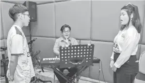  ??  ?? MINAT: Tenaga pengajar muzik program Genius Remaja, Shahrol Bahri Shaarani (tengah) mengajar vokal kepada Syaidatul Kamra (kanan) dan Muhammad Ismail Sulaiman (kiri).