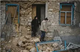  ?? DANIEL COLE/AP ?? Oleksandra Hryhoryna, left, inspects her house Saturday, damaged by shelling last fall in Kalynivske, Ukraine. Villagers are still suffering with no electricit­y or water.