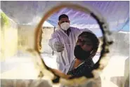  ?? AP ?? A worker takes a swab at a COVID-19 testing site in India, where two vaccines were approved Sunday. See story, A8.