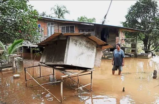  ?? — Bernama ?? Surveying the damage: Azhar Othman, 56, a resident of Kampung Gudang Rasau in Kuantan, checking his chicken coop after floods in the area receded.