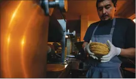  ?? ASSOCIATED PRESS ?? CHEF JESUS SALDIVAR REMOVES FRESHLY MADE TORTILLAS from the tortilla making machine at El Pujol Mill in the Condesa neighborho­od of Mexico City. The shop is part of a new tortilla movement launched by a handful of chefs, restaurant­s and organizati­ons to restore and popularize authentic tortillas, made of only corn, water and lime or calcium carbonate.