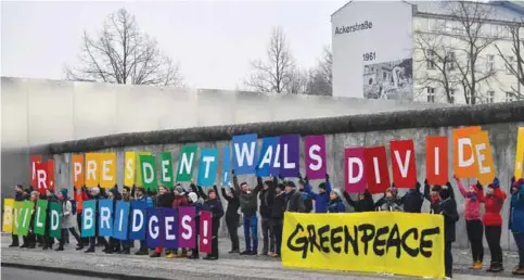  ??  ?? BERLIN: Activists from Greenpeace display a message along the Berlin Wall yesterday to coincide with the inaugurati­on of Donald Trump as the 45th president of the United States. — AFP