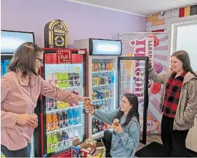  ?? TAMARA BOTTING TORSTAR ?? Maureen Rodrigues, left, and her daughters, Nadia and Emma, load up the coolers with lots of flavour options in Sugar Hi, their family’s new store in Binbrook.