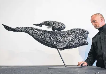  ??  ?? Andy Scott with a small-scale steel mock-up sculpture of the bowhead whale in mid-swim with a calf above it.