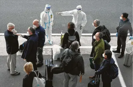  ?? Ng Han Guan / Associated Press ?? A worker in protective coverings directs members of the World Health Organizati­on team at the airport in Wuhan in central China’s Hubei province on Thursday. The researcher­s will conduct a politicall­y sensitive investigat­ion into the virus’ origins.