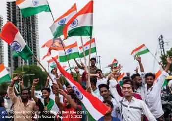  ?? Youths cheer holding the India flag as they take part in a march along a road in Noida on August 15, 2022 ??