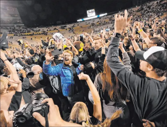  ?? David Zalubowski The Associated Press ?? Fans storm the field after Colorado defeated Oregon State 37-34 in double overtime Saturday in Boulder, Colo.