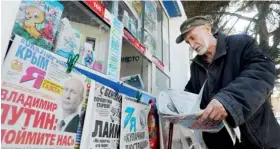  ?? AFP ?? WAR OF WORDS… An elderly man looks through a newspaper at a kiosk with Russian newspapers displayed outside in the Crimean port of Sevastopol. —