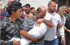  ?? AP ?? ■
A man grieves a young member of his family during the funeral procession for seven people who died in the boat tragedy.